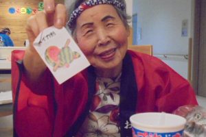 入居者が作成した絵画作品を笑顔で掲げている様子