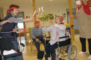入居者がスタッフと共にクリスマス飾りの前で季節行事を楽しむ風景